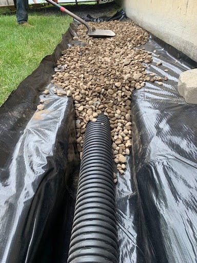 Drainage pipe installation with gravel and landscaping fabric
