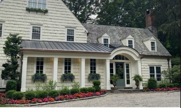 Elegant home exterior with professional seasonal plantings and red flowers
