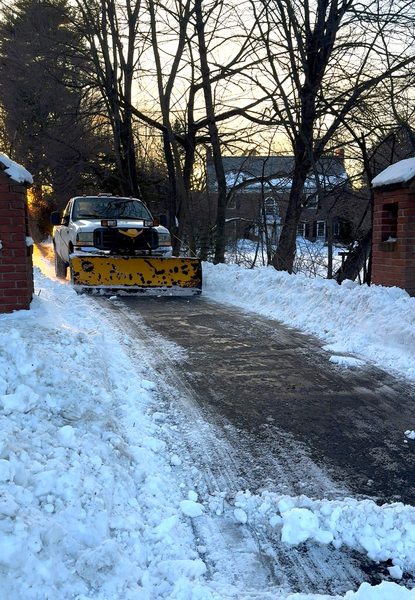 Snow plow clearing a residential driveway after a winter storm